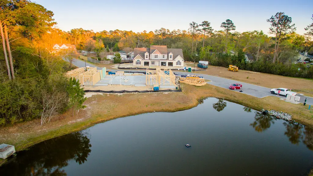Aerial view of active townhome construction around a pond at Azalea Square